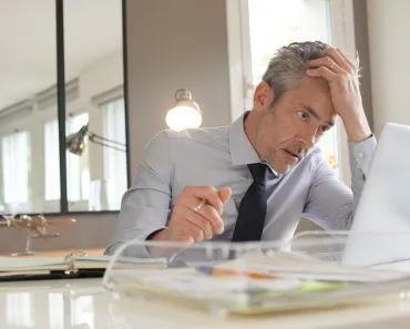 Stressed,Businessman,Working,In,Contemporary,Office