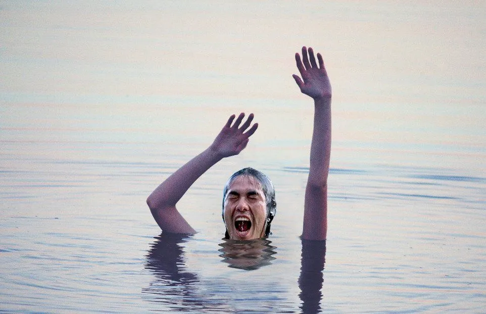 Boy waving arms in water for help