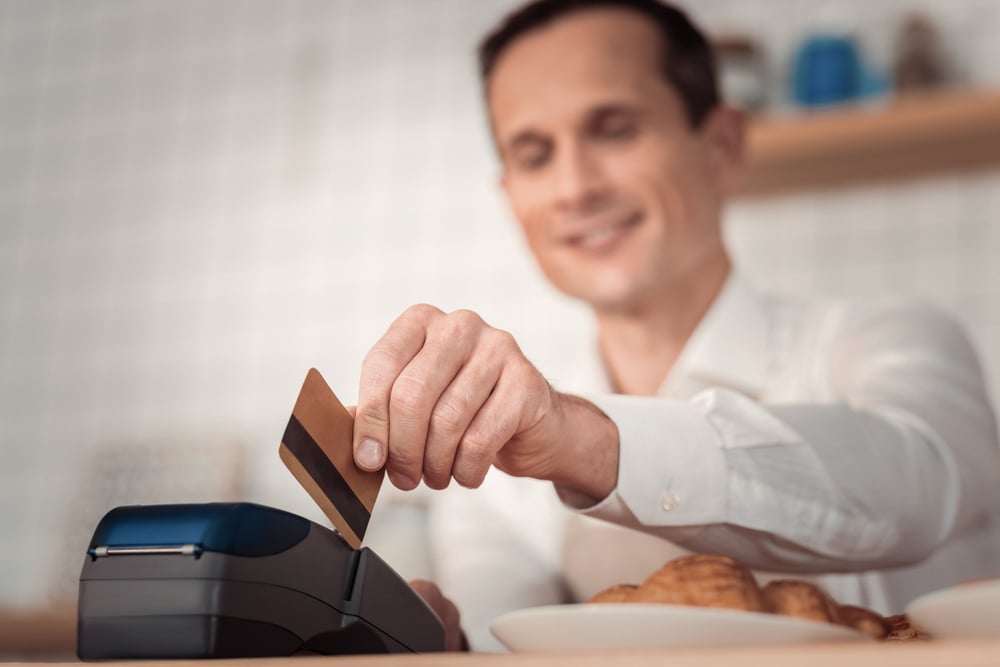 Financial operation. Selective focus of a credit card being in use by a nice joyful man while making non cash payment - Image( YAKOBCHUK VIACHESLAV)s