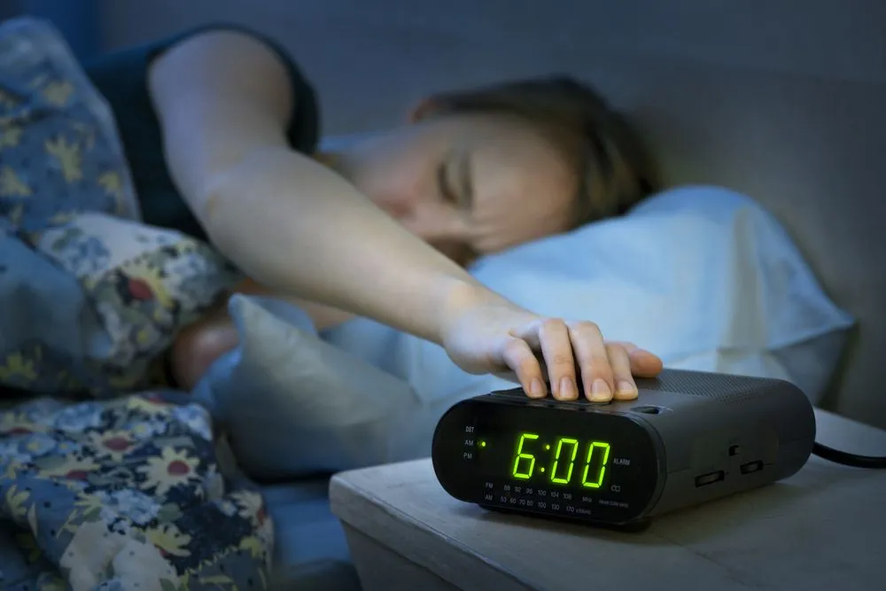 Young woman pressing snooze button on early morning digital alarm clock radio - Image( Elena Elisseeva)s