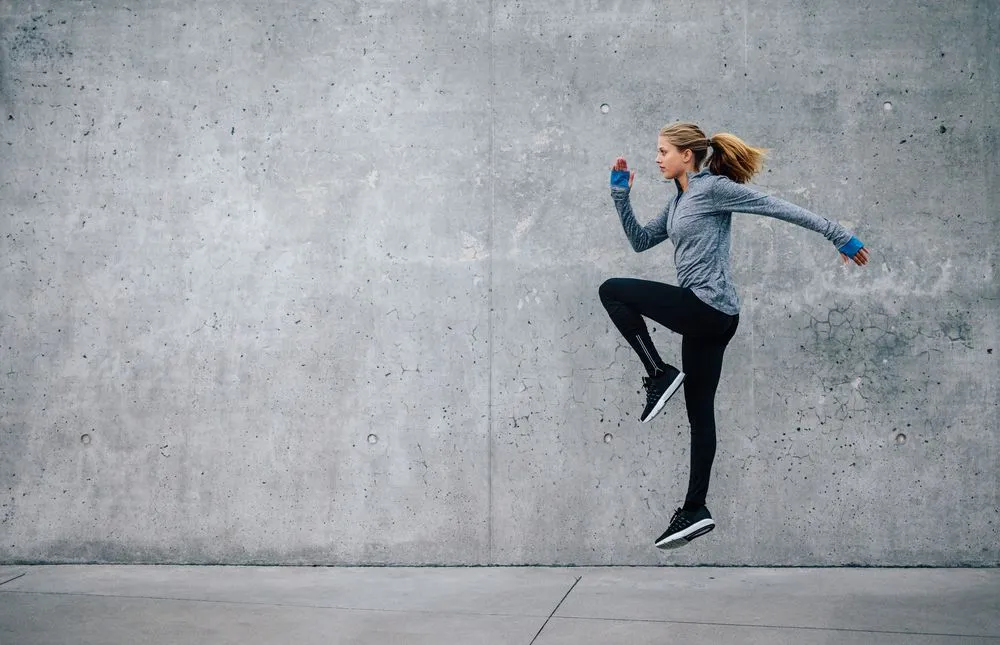 Side view shot of fit young woman doing cardio interval training against grey background( Jacob Lund)S