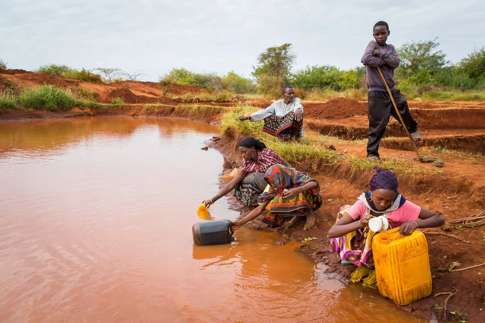Women and young village girls collect water from a rain water pool which is purified before use with tablets(Martchan)s