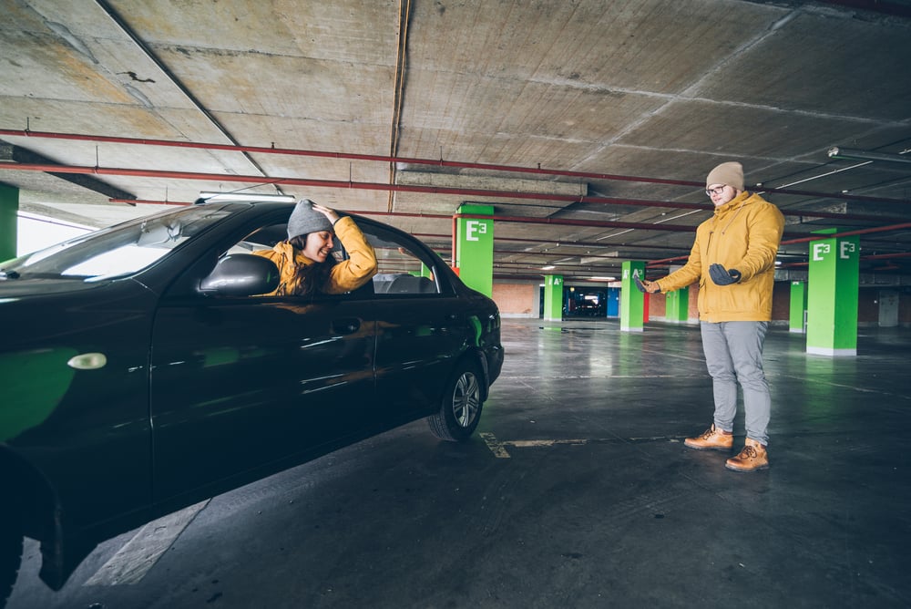 unconfident young woman parking car on empty spot in underground parking with man help( Vera Petrunina)s