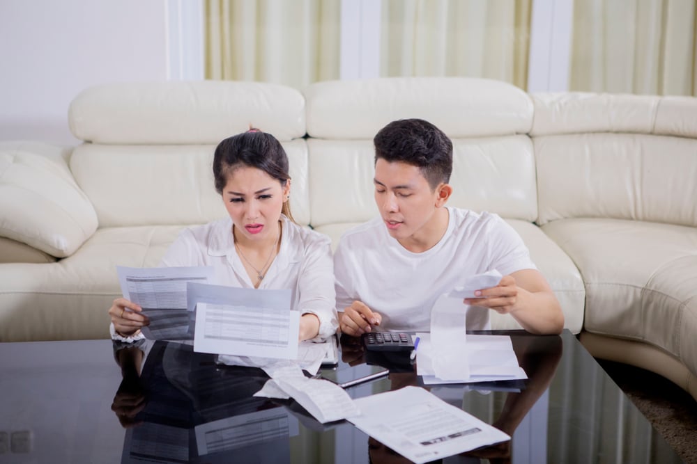 Picture of young couple looks stressed while checking their high expenses(Creativa Images)s
