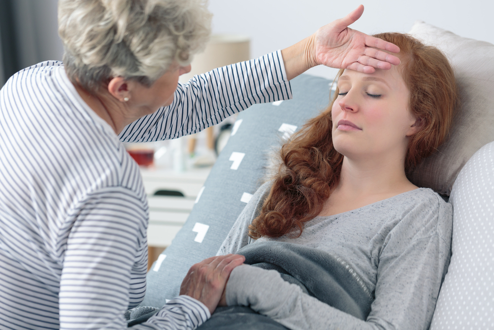 Grandma,Checking,Temperature,Of,Sick,Granddaughter,Lying,In,Bed,With