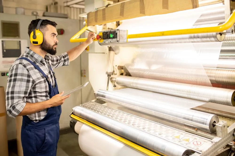 Serious young engineer of chemical production factory taking control of process of making polyethylene film