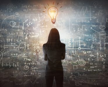 Young,Woman,Looking,On,The,Black,Board,With,Mathematical,Formulas