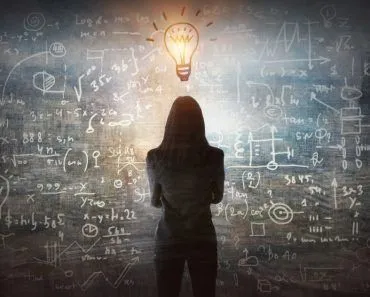 Young,Woman,Looking,On,The,Black,Board,With,Mathematical,Formulas